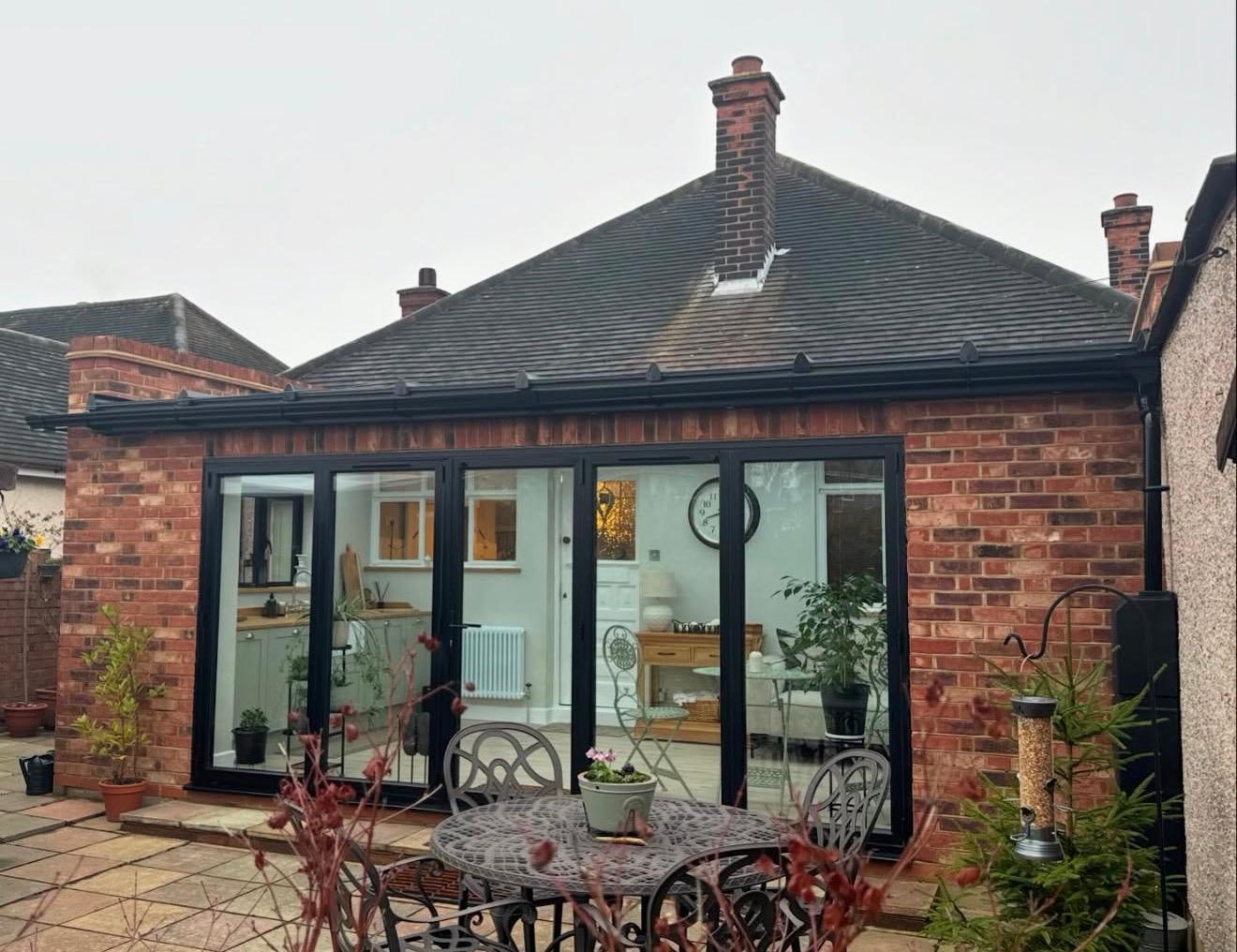 Red brick orangery-style rear extension with anthracite bifold doors