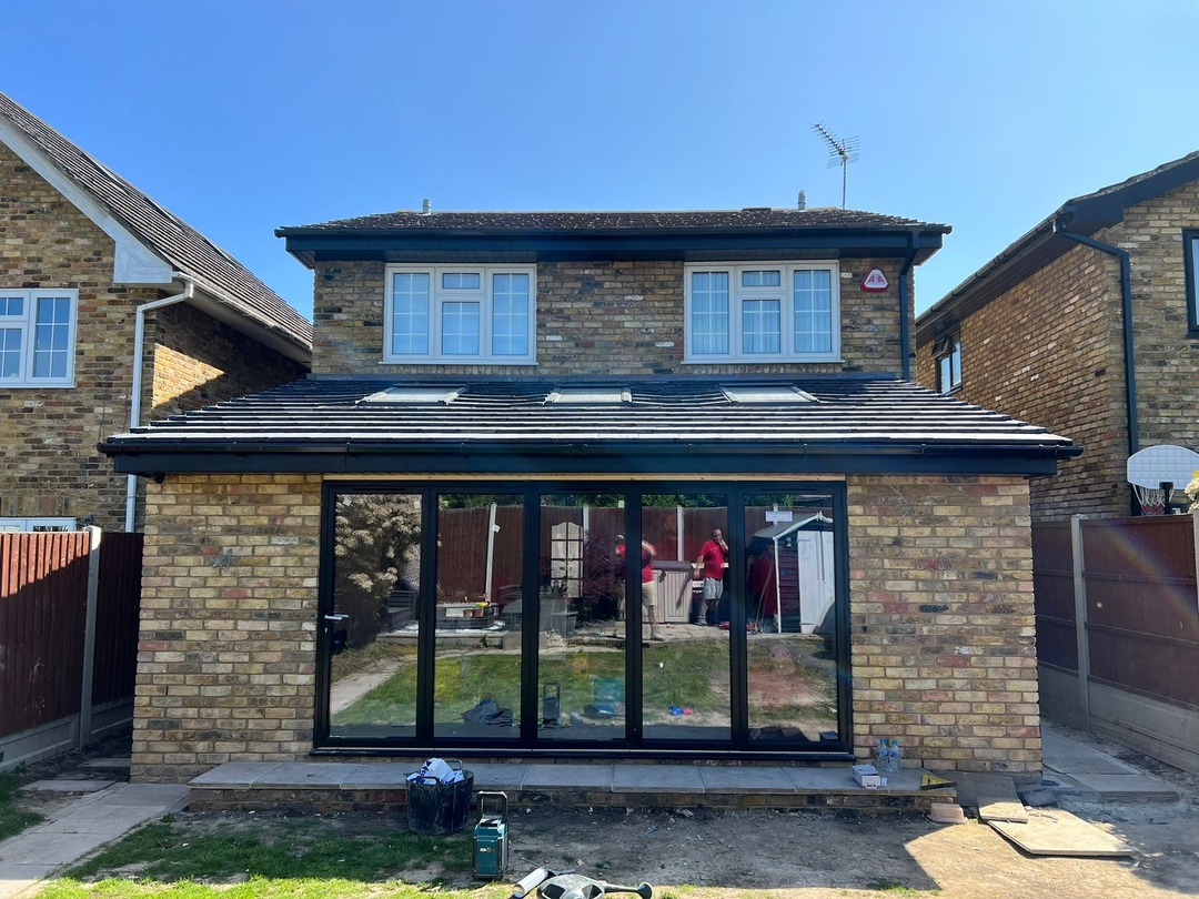 Completed rear extension with full-width black-framed bifold doors and pitched tiled roof with rooflights